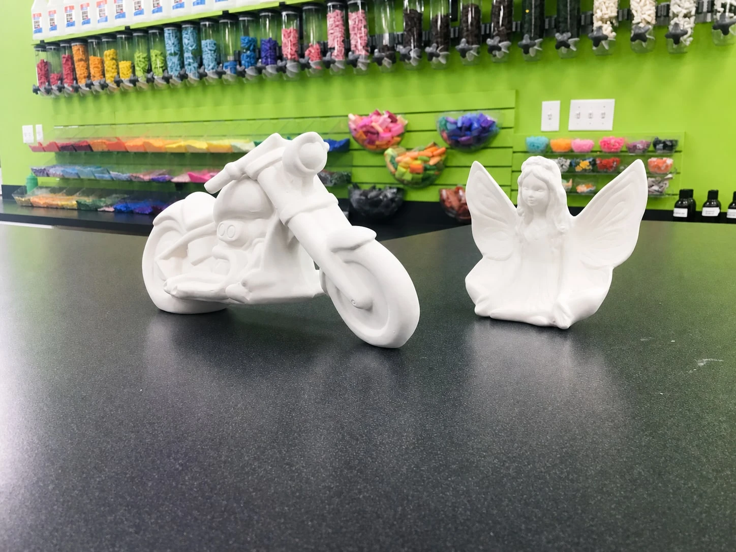 Unpainted motorcycle and fairy ceramic figurines in the studio