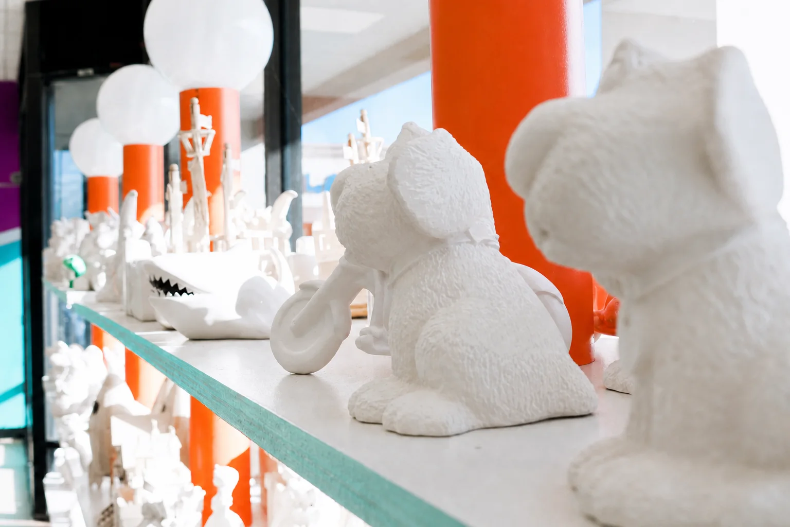 Different unpainted ceramic figurines displayed on a studio shelf