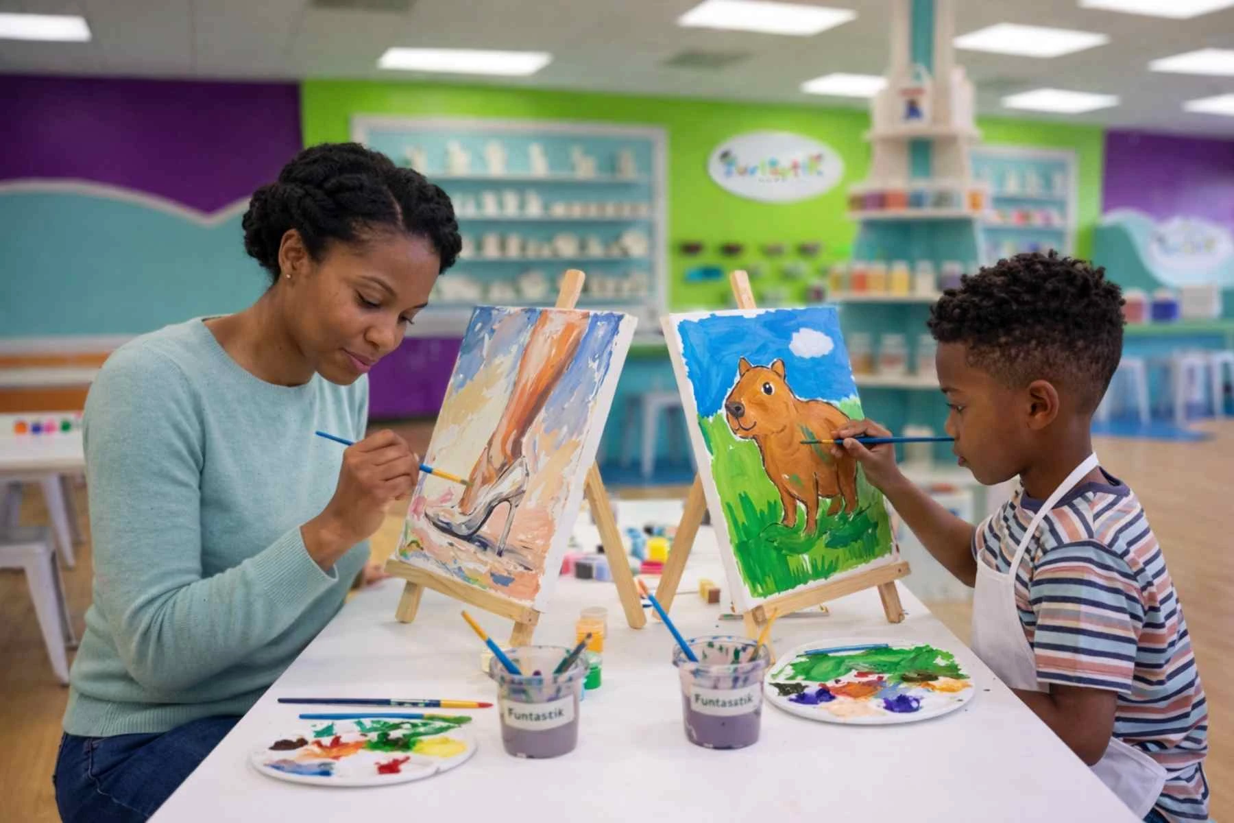 A parent and child painting pre-drawn canvases together at Funtastik Labs