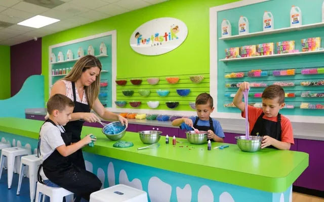 A family mixing and stretching colorful slime at Funtastik Labs